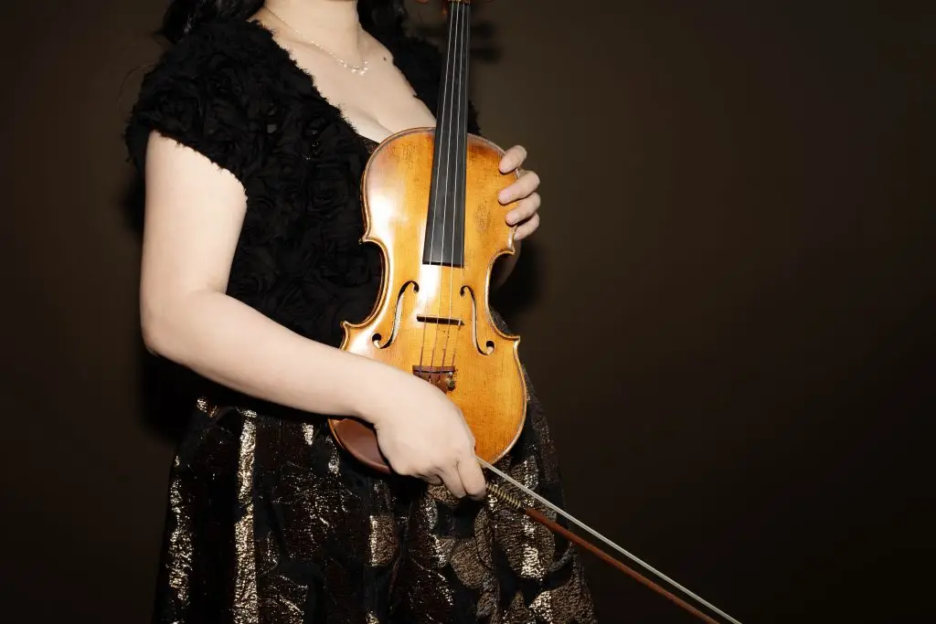 Acoustic violin in center, held by female violinist